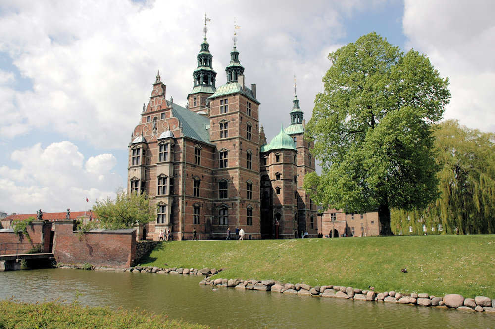 Bilde av utsiden til Rosenborg Slot i København: grønt gress, trær og kanal
